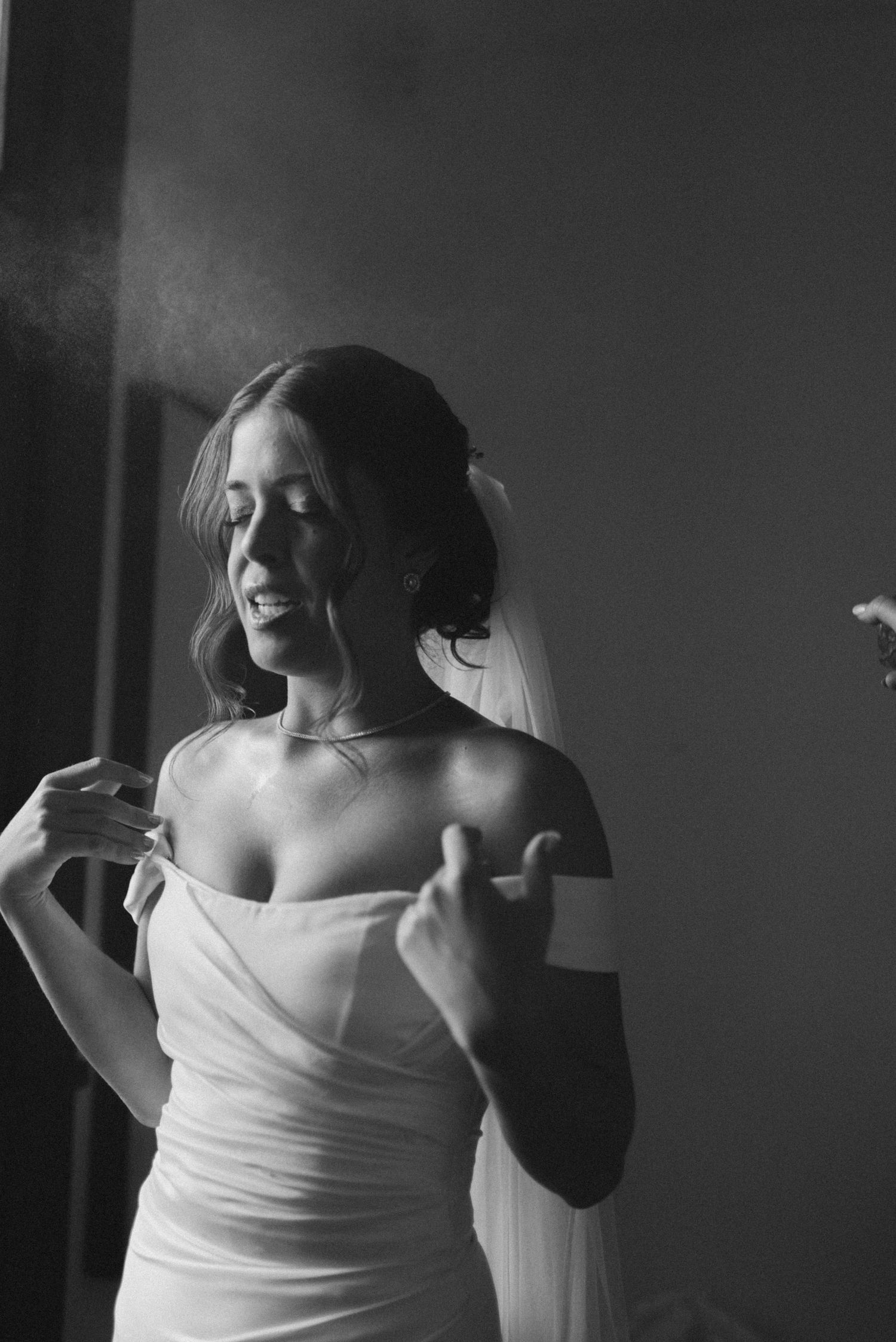 Black and white portrait of person in off-shoulder wedding dress with veil.