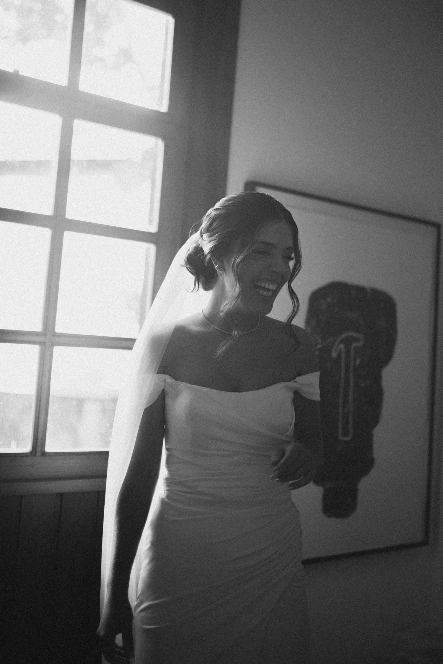 Black and white candid moment of joy captured during bridal preparations.