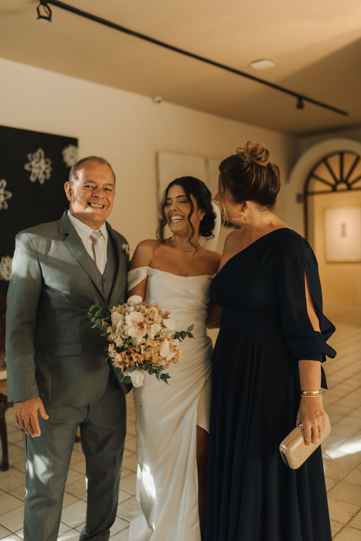 Wedding party members share a joyful moment in an elegant indoor venue with warm lighting.