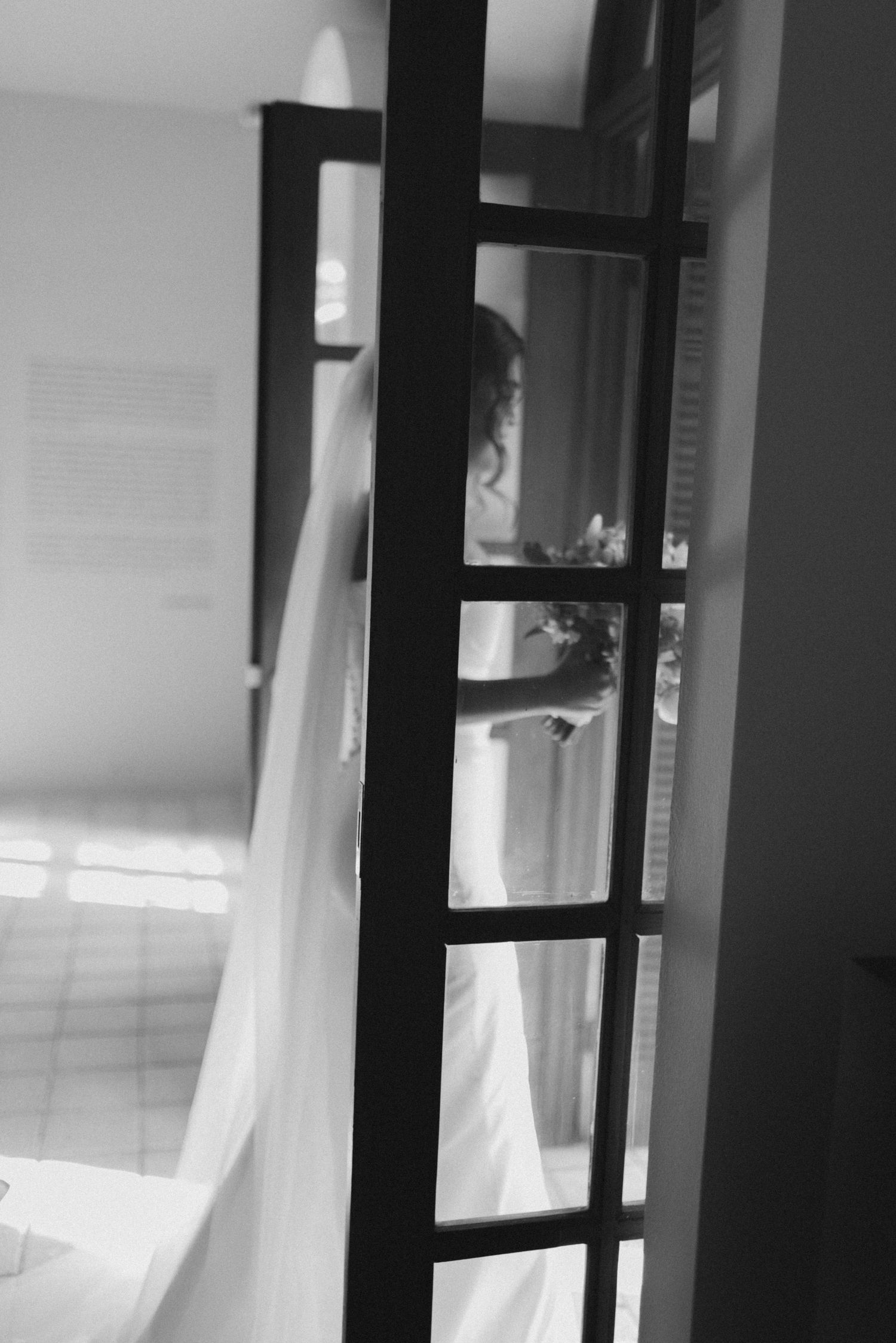 Black and white photo of a silhouette through a divided glass door panel.