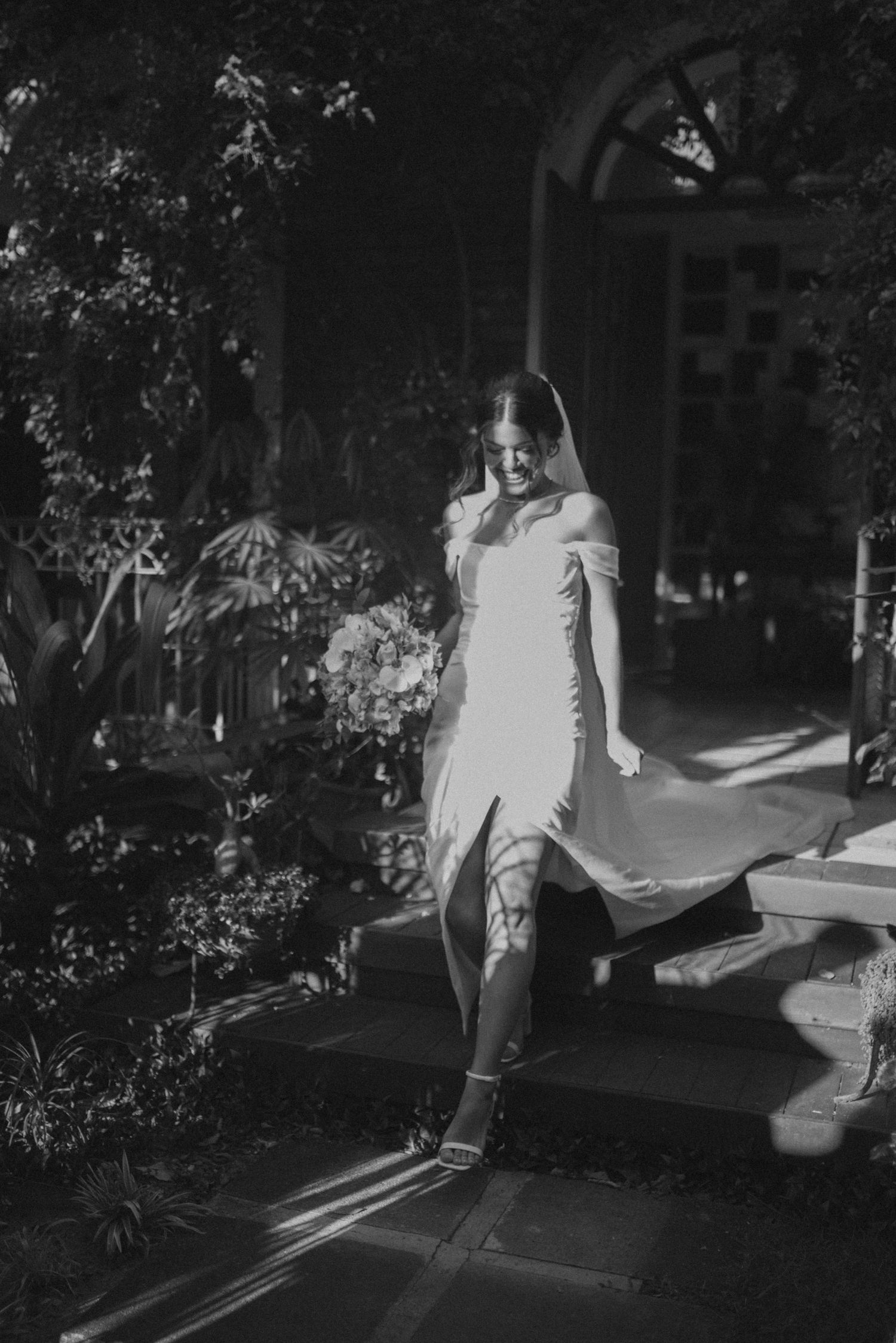 Black and white portrait on garden steps with dramatic shadows and architectural details.