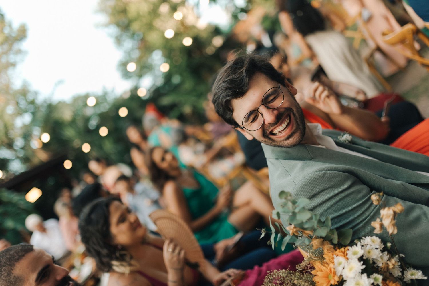 Joyful celebration at outdoor wedding reception with string lights and greenery.