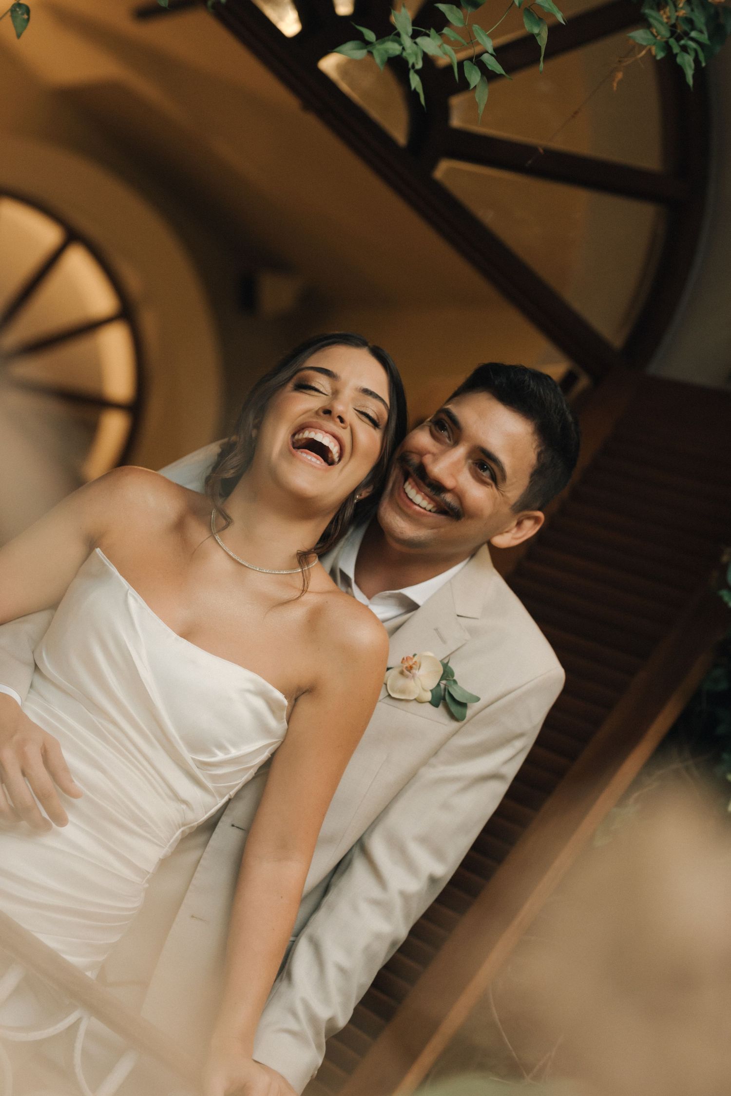 Candid moment of laughter shared between newlyweds under architectural details.