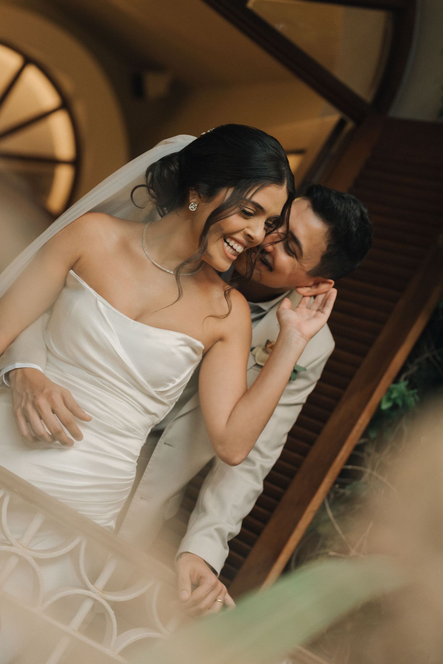 Romantic candid moment between newlyweds sharing laughter indoors.