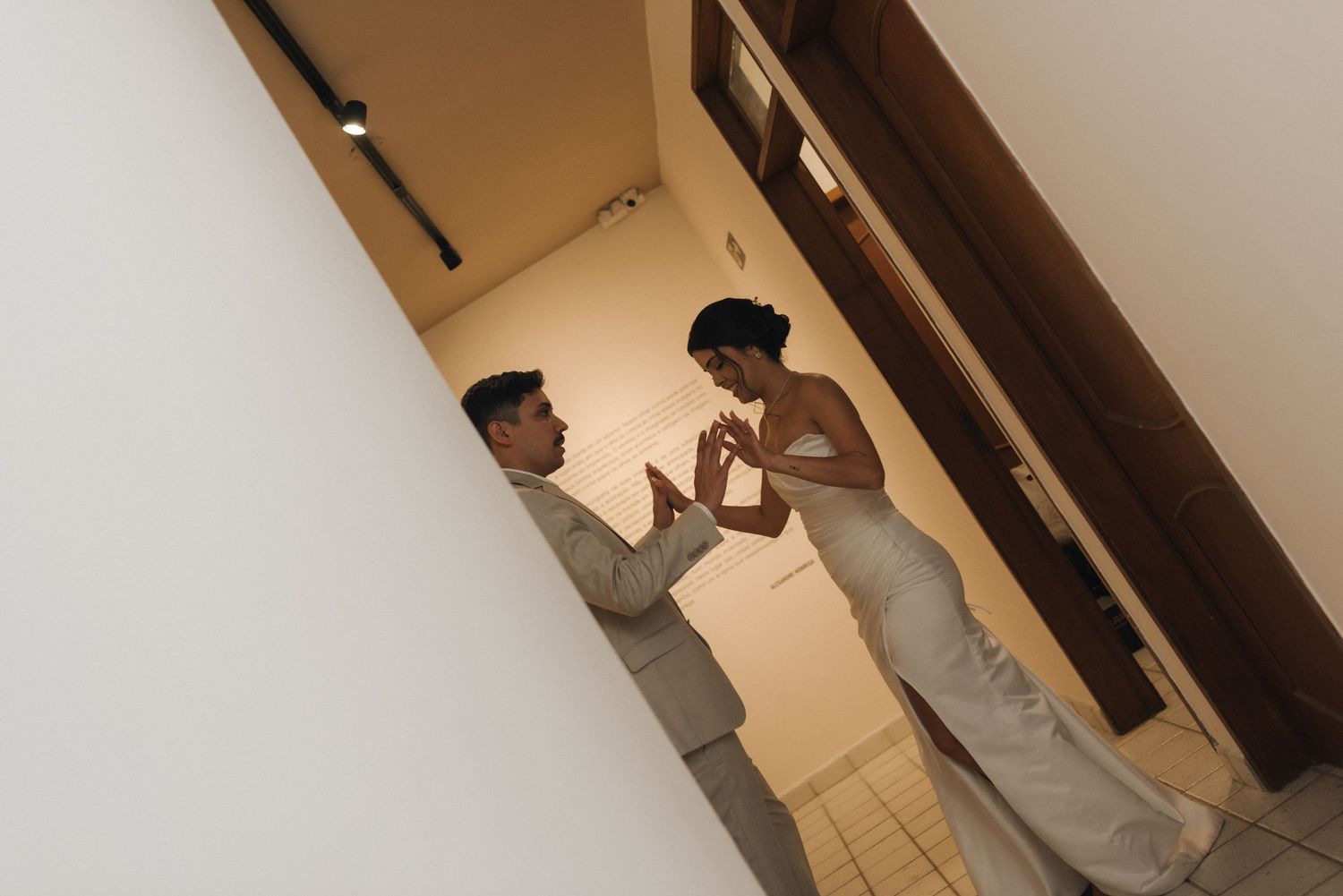 Candid moment between wedding couple in narrow hallway.