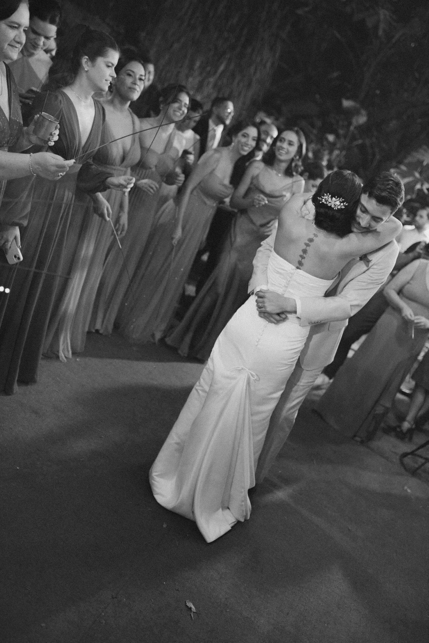 A couple performs their first dance at a wedding reception while guests watch from the sidelines.