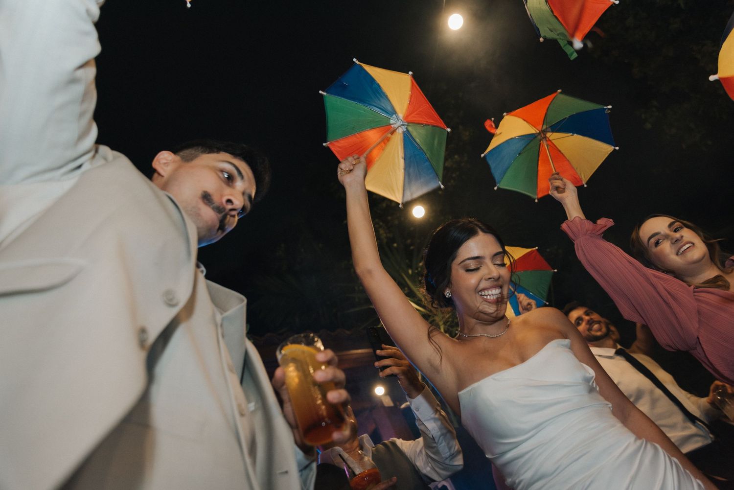 Wedding celebration with guests holding colorful umbrellas on the dance floor.
