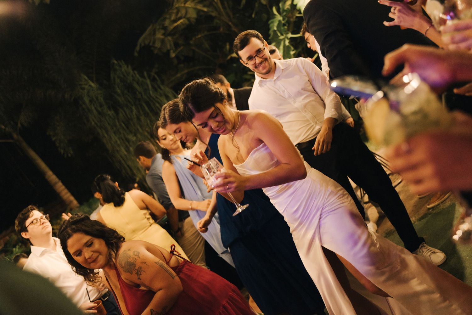 Wedding guests dancing and celebrating on a festively lit outdoor dance floor.