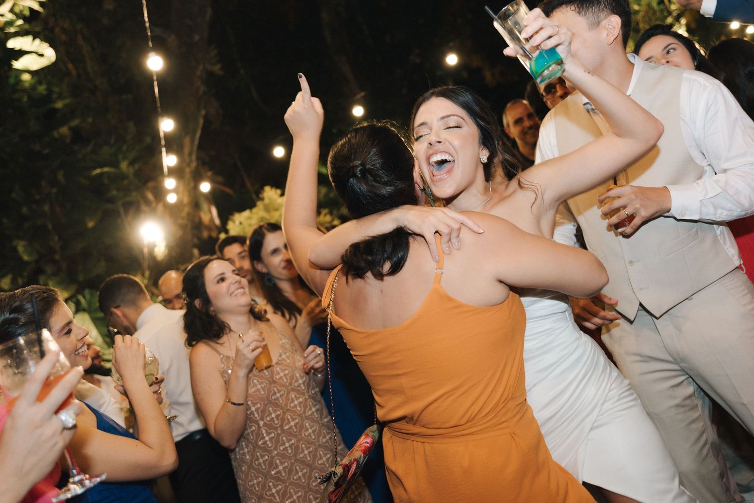 Joyful crowd dancing and celebrating at an outdoor summer party.