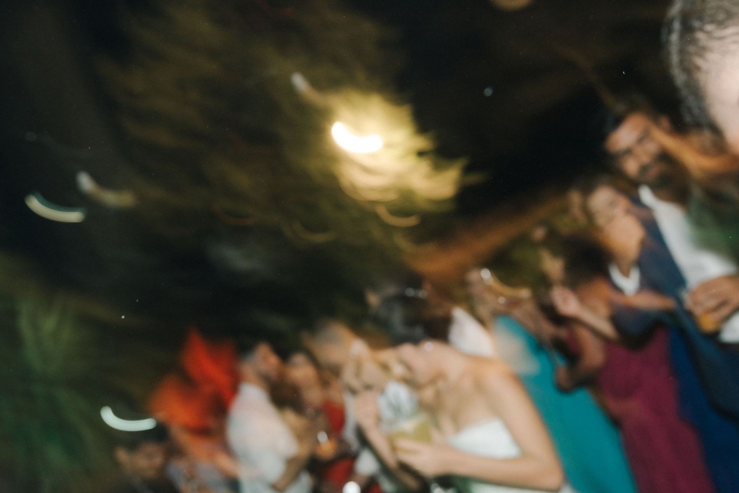 Blurred motion shot of people dancing at a nighttime celebration.