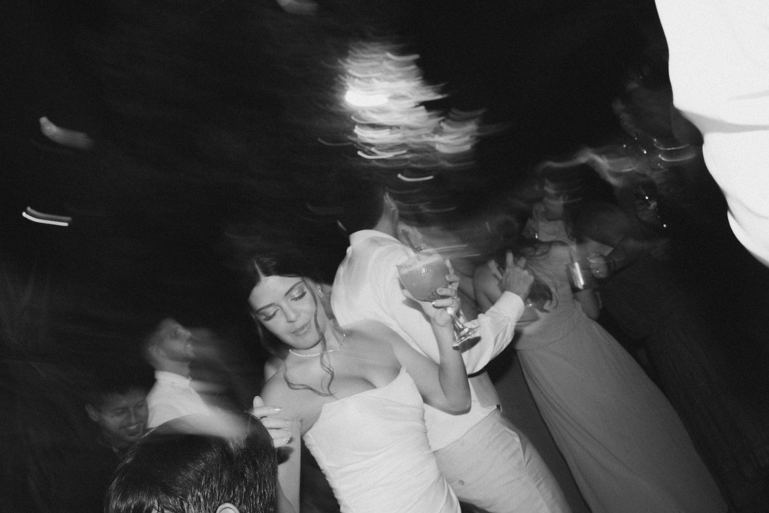Black and white candid shot of people dancing at a celebration.