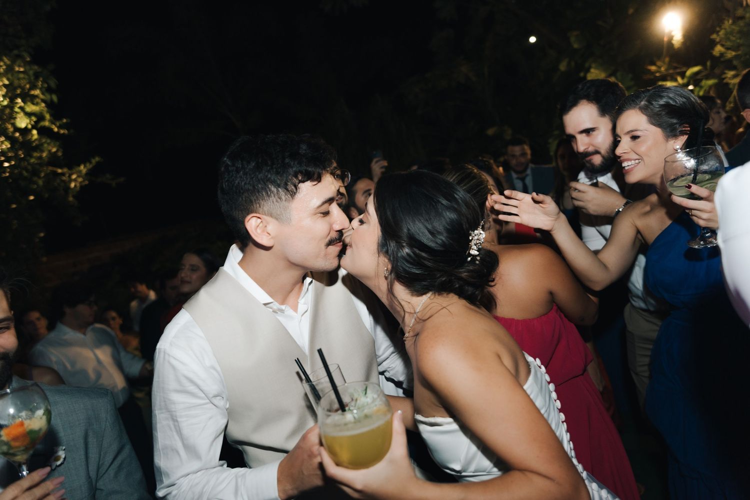 Couple sharing an intimate moment while dancing with cocktails at an evening celebration.
