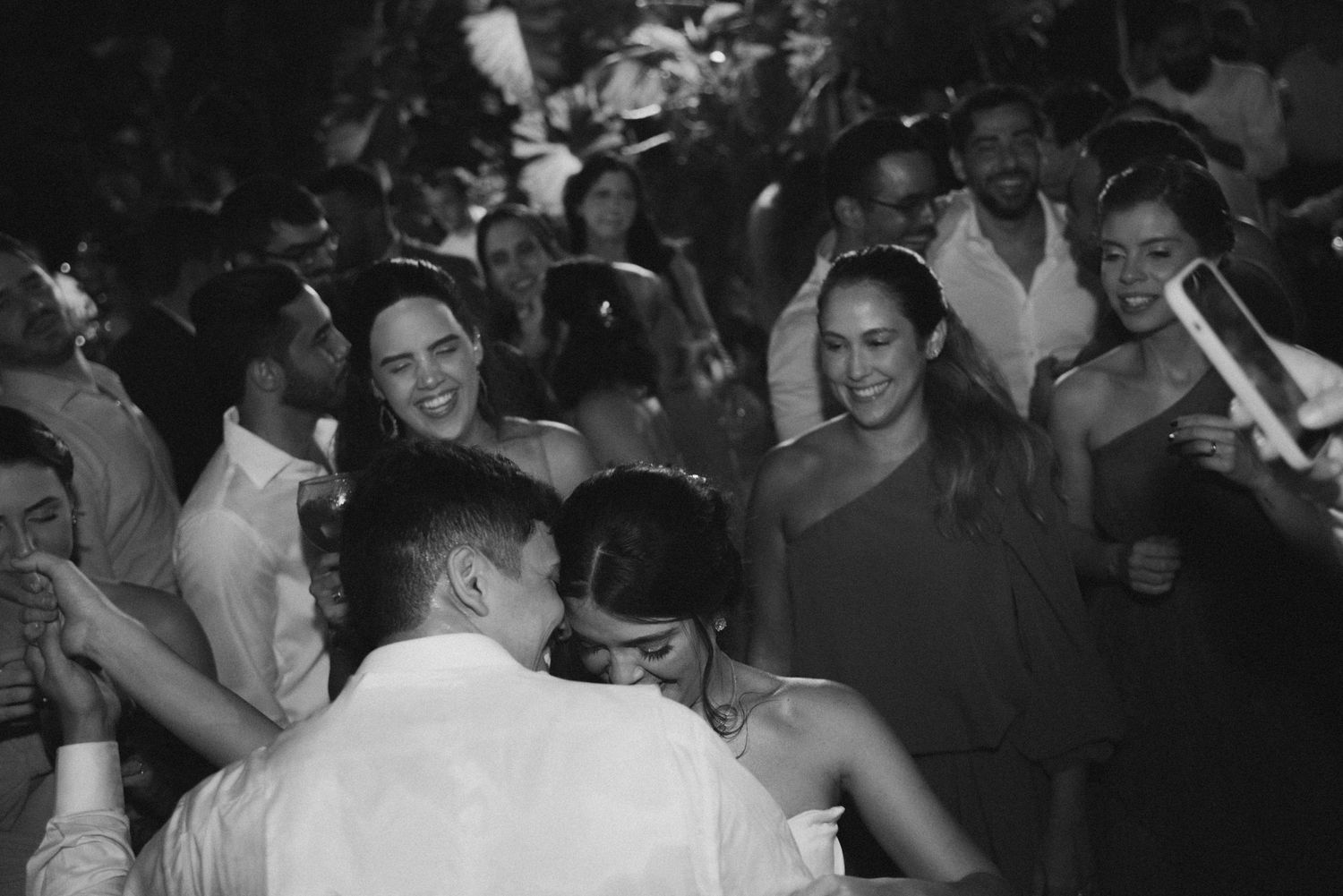 Black and white photo of party guests dancing and celebrating at a crowded event.