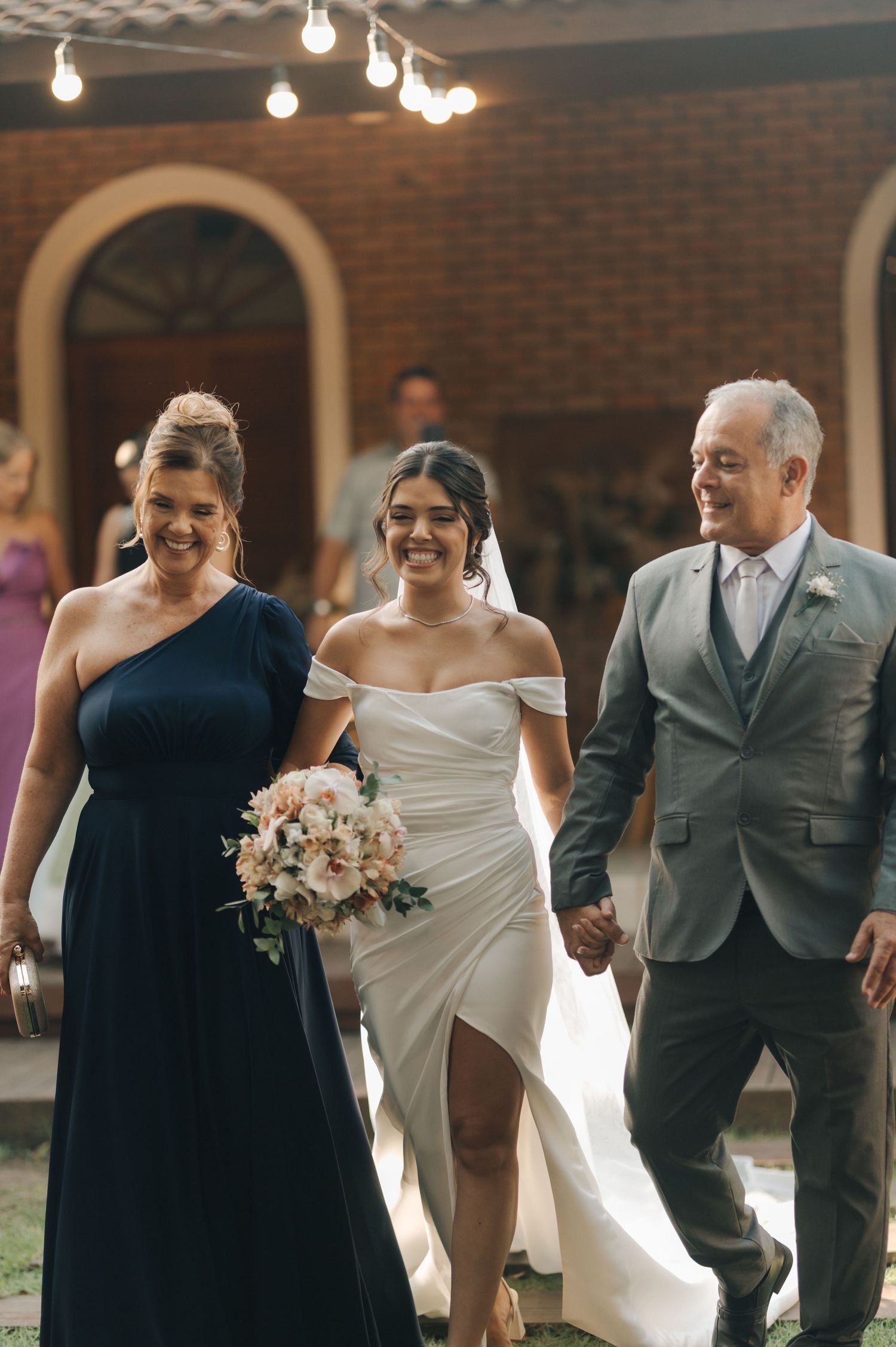 Wedding party walking down outdoor venue steps with string lights overhead.