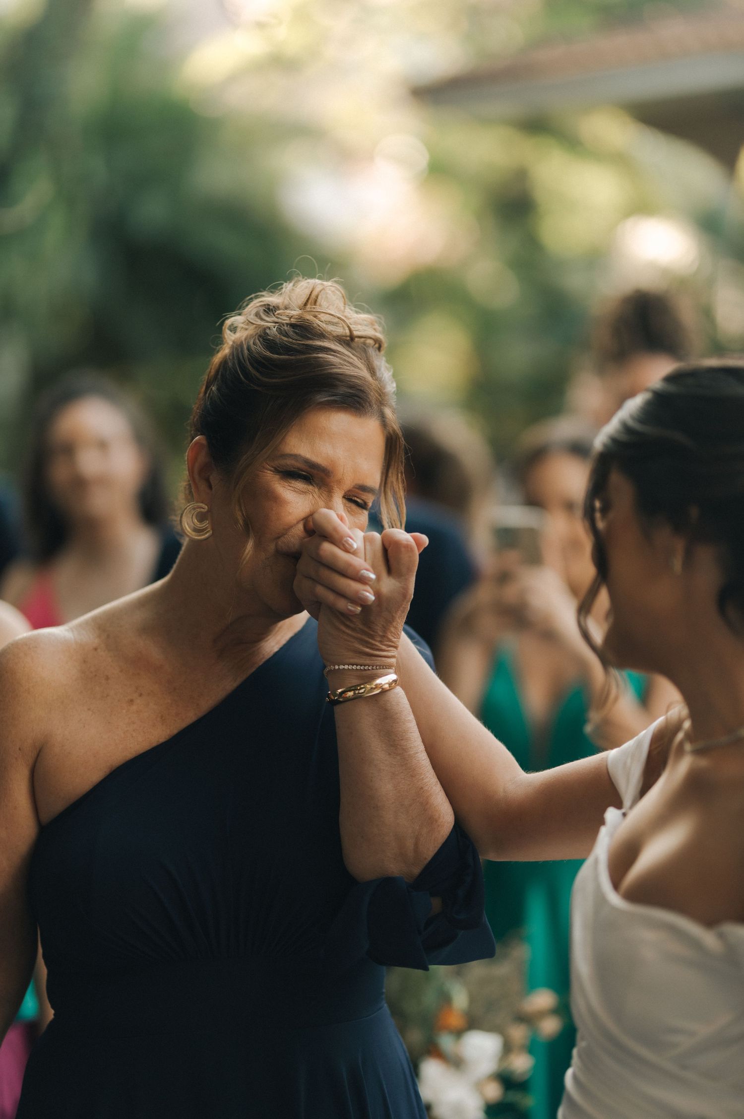 Woman in navy dress showing emotional reaction during wedding ceremony.