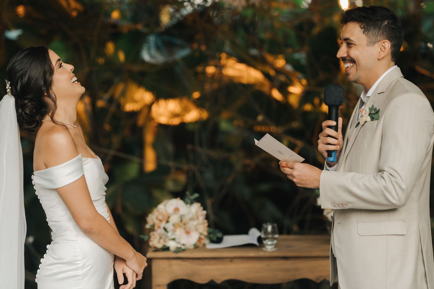 A joyful wedding ceremony moment as the couple exchanges vows under twinkling lights and greenery.