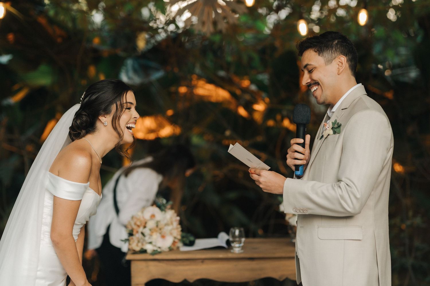A couple shares a candid laugh during their outdoor wedding vows ceremony.