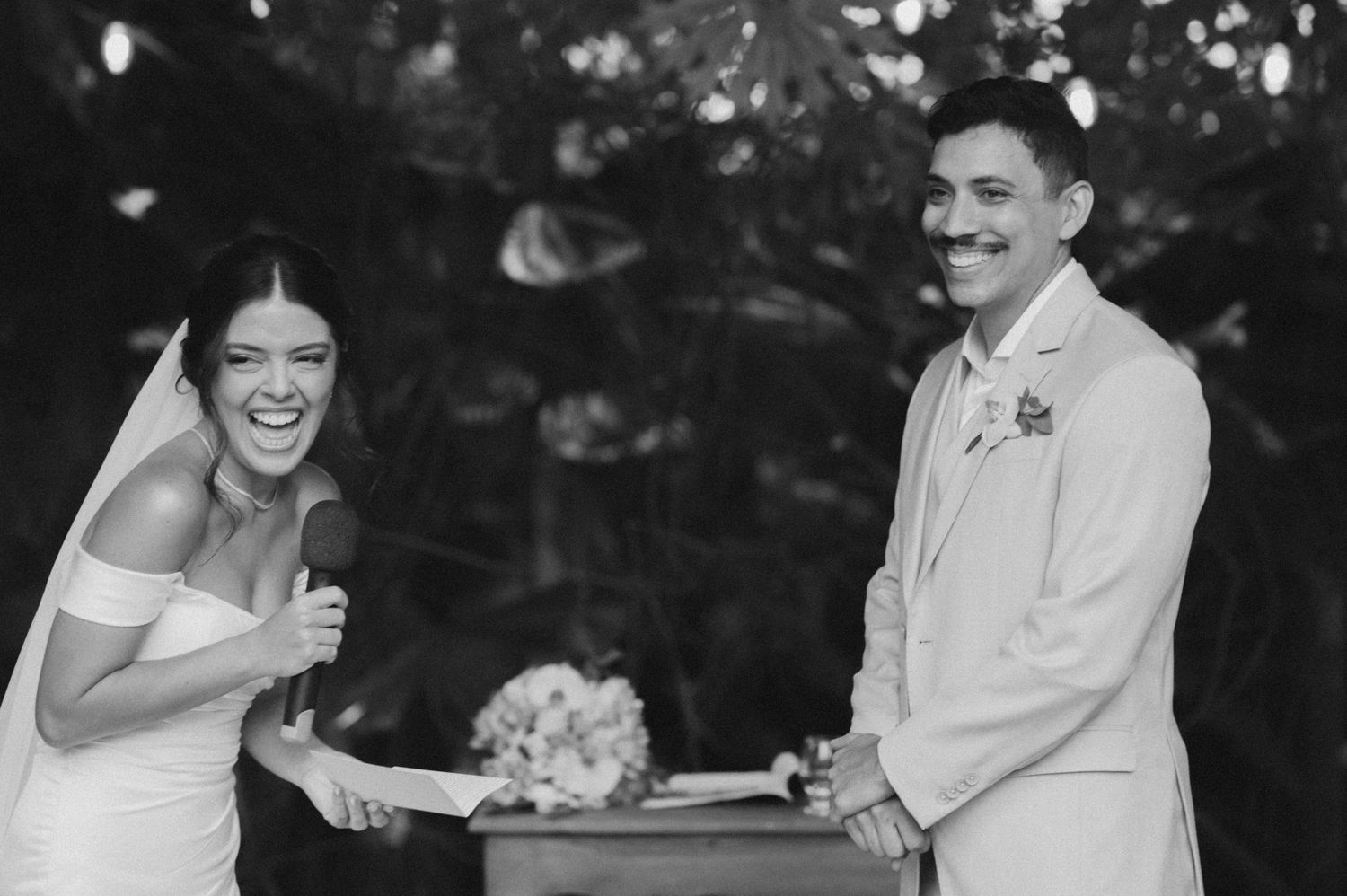 Black and white capture of a couple sharing laughter during their wedding ceremony.