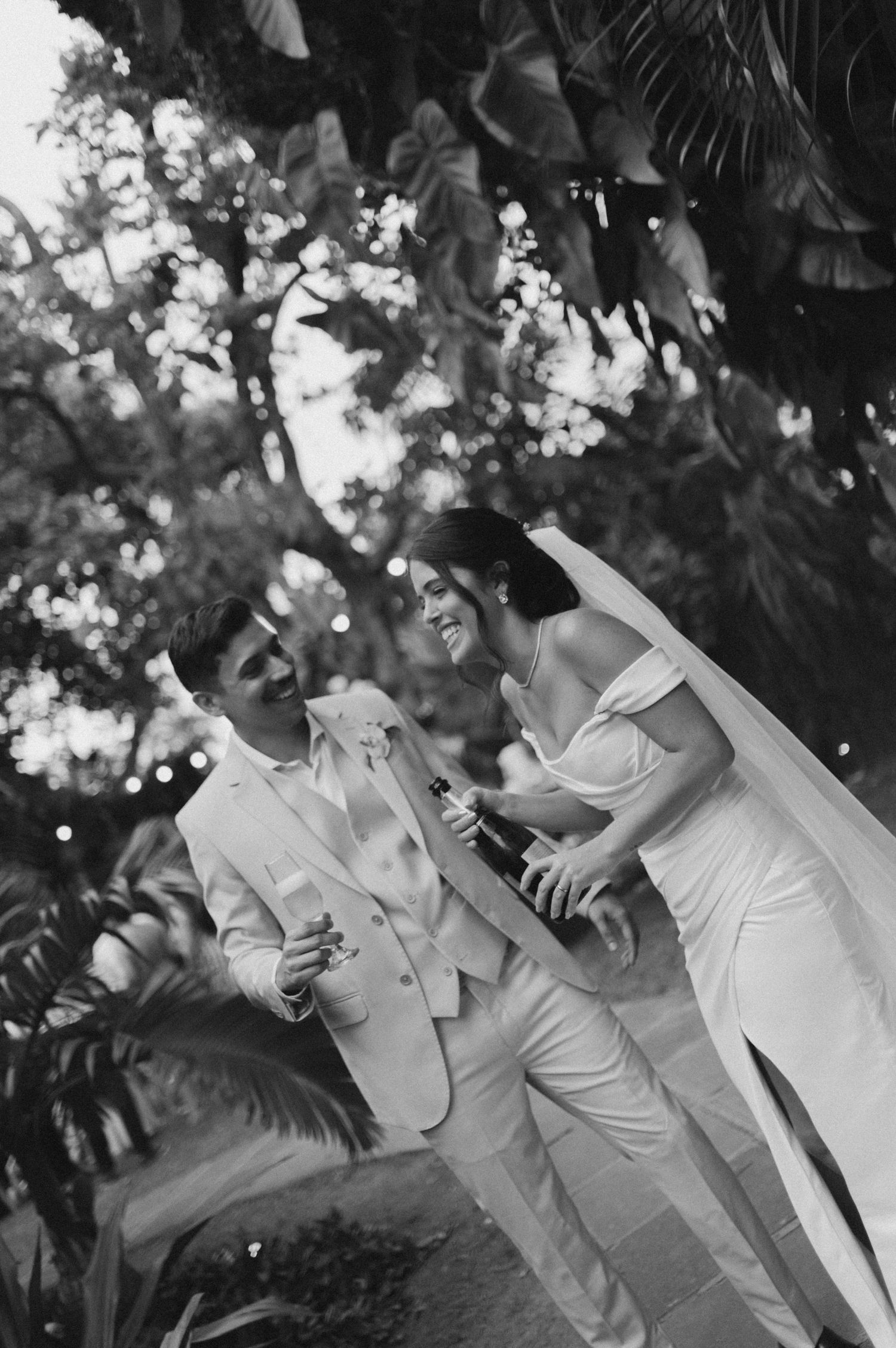 Black and white photo of a couple laughing together during their wedding celebration.
