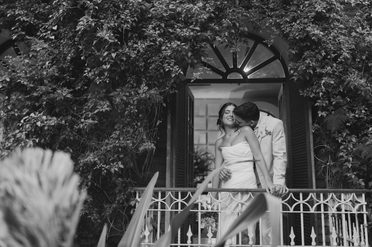 Black and white photo of a couple posing on a balcony with decorative railings.