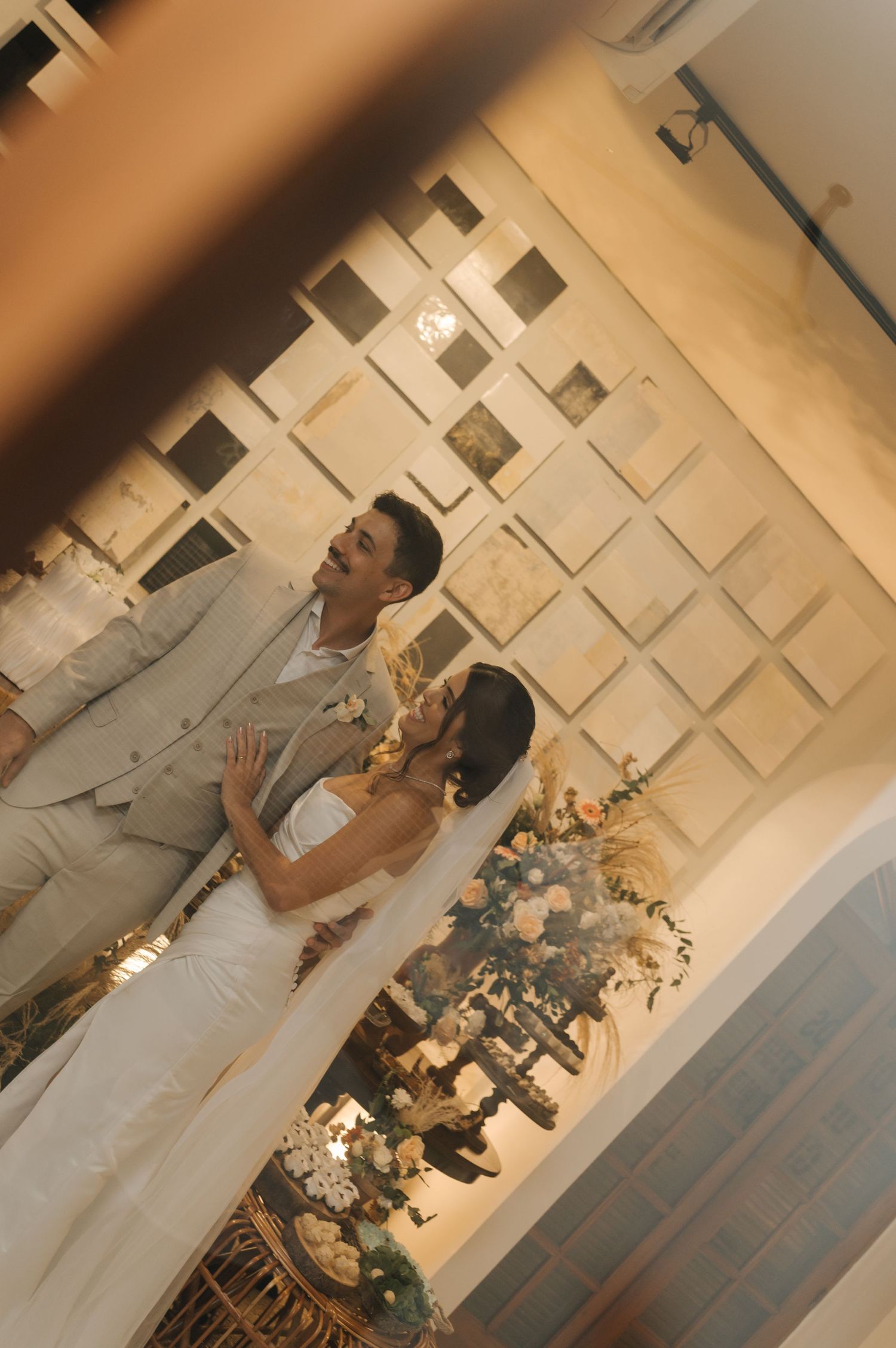 A wedding celebration in an elegant venue with geometric wall decor and floral arrangements.