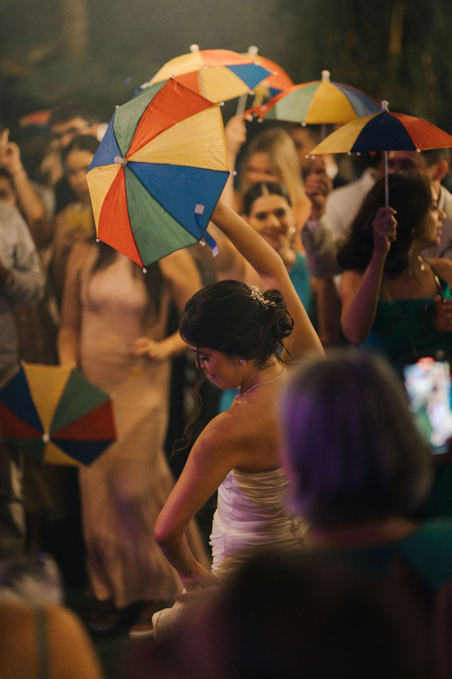 Wedding guests holding colorful umbrellas during a festive celebration.