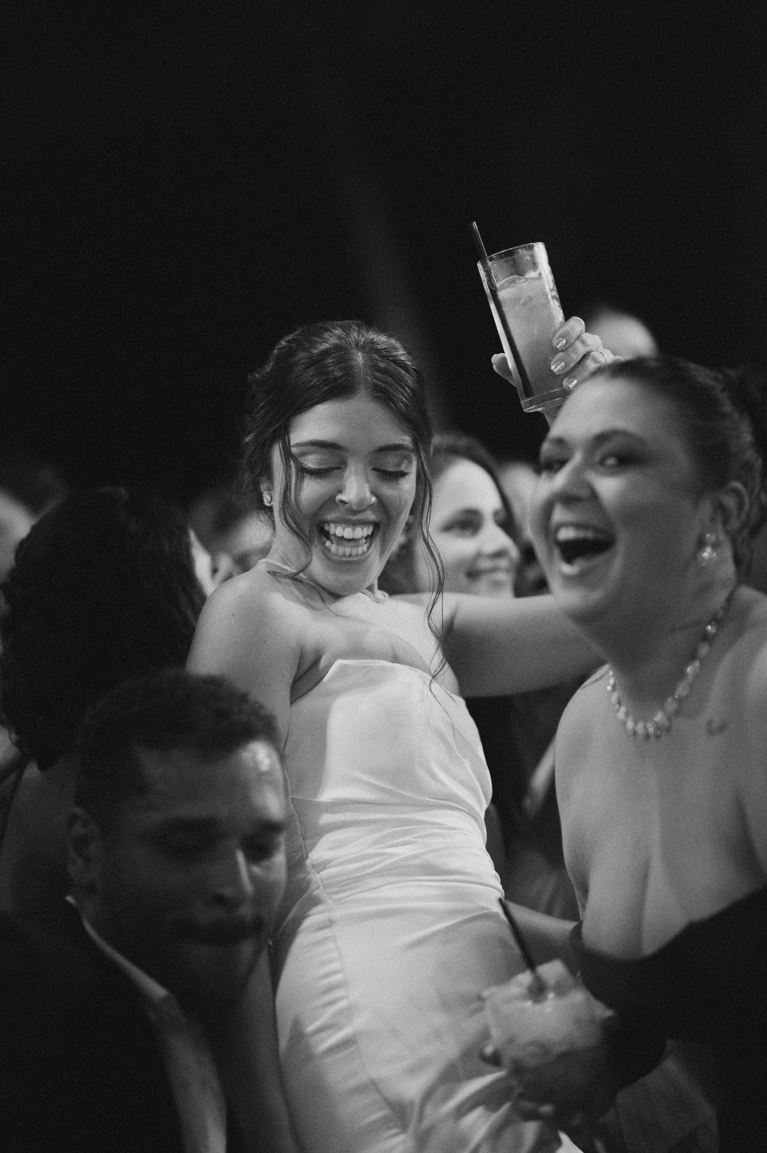 A candid black and white photo capturing laughter and joy during wedding festivities.