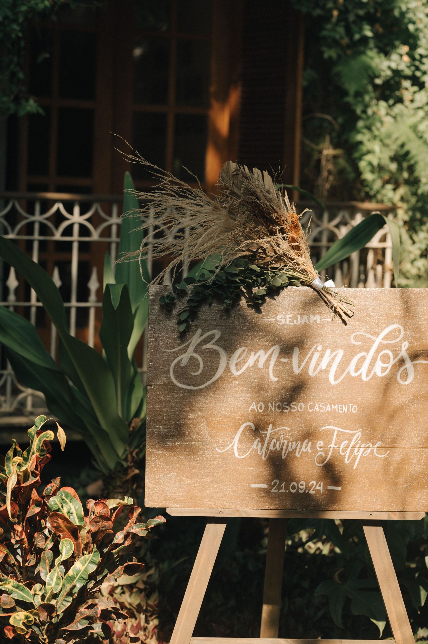 Rustic welcome sign with dried flowers for a wedding ceremony.