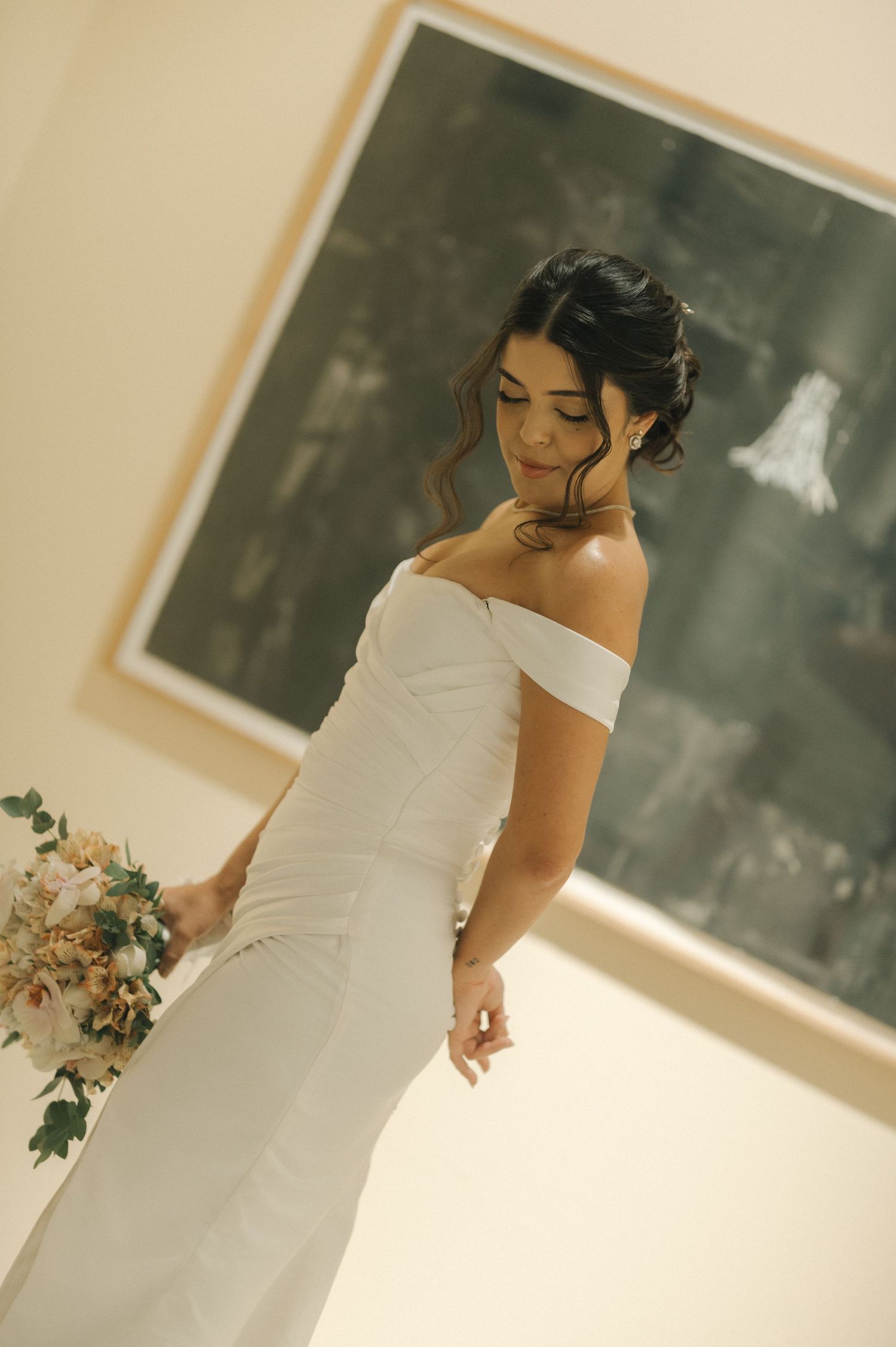 An elegant off-shoulder wedding dress photographed in a minimalist setting.