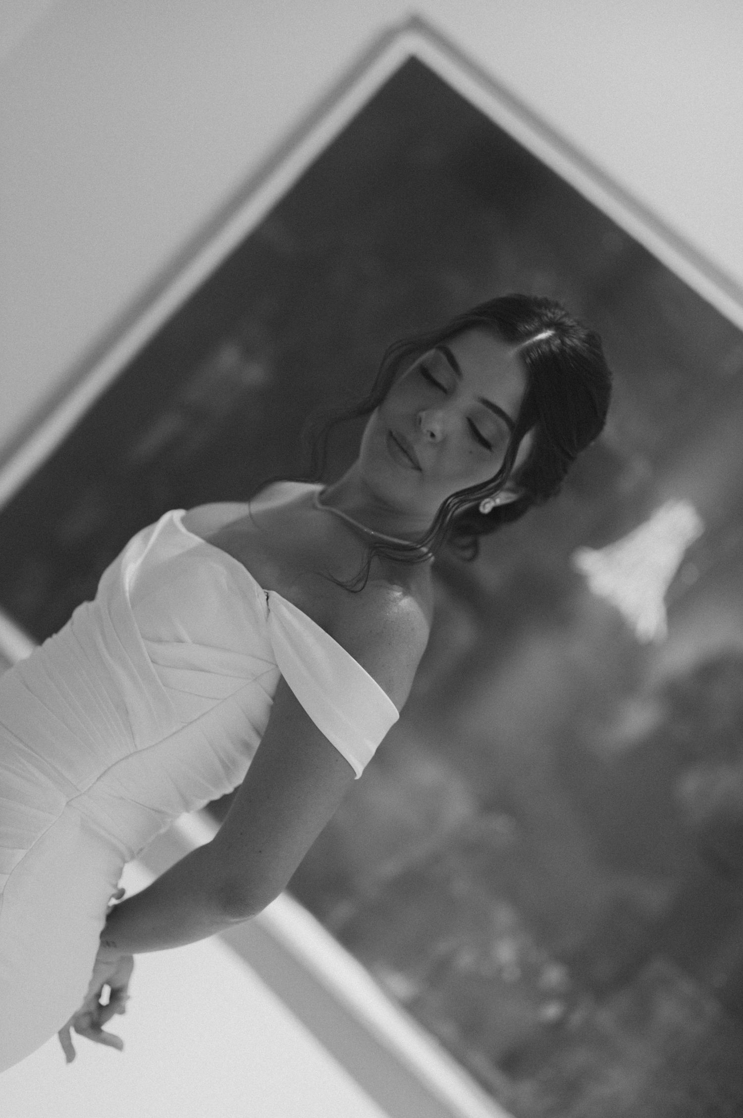 A black and white portrait showing the details of an off-shoulder wedding gown.