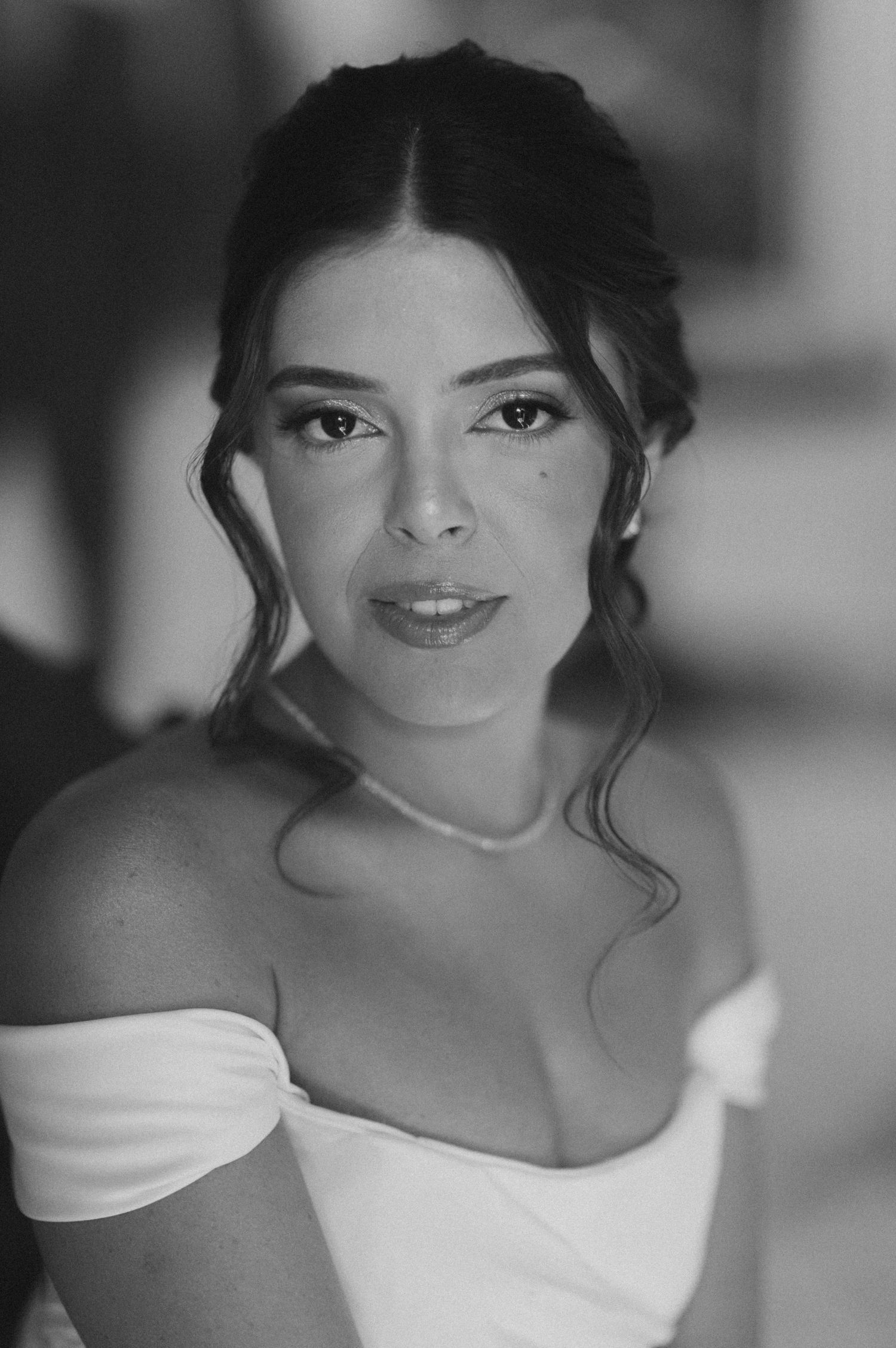 Portrait of a person in a white off-shoulder dress with an elegant updo hairstyle.