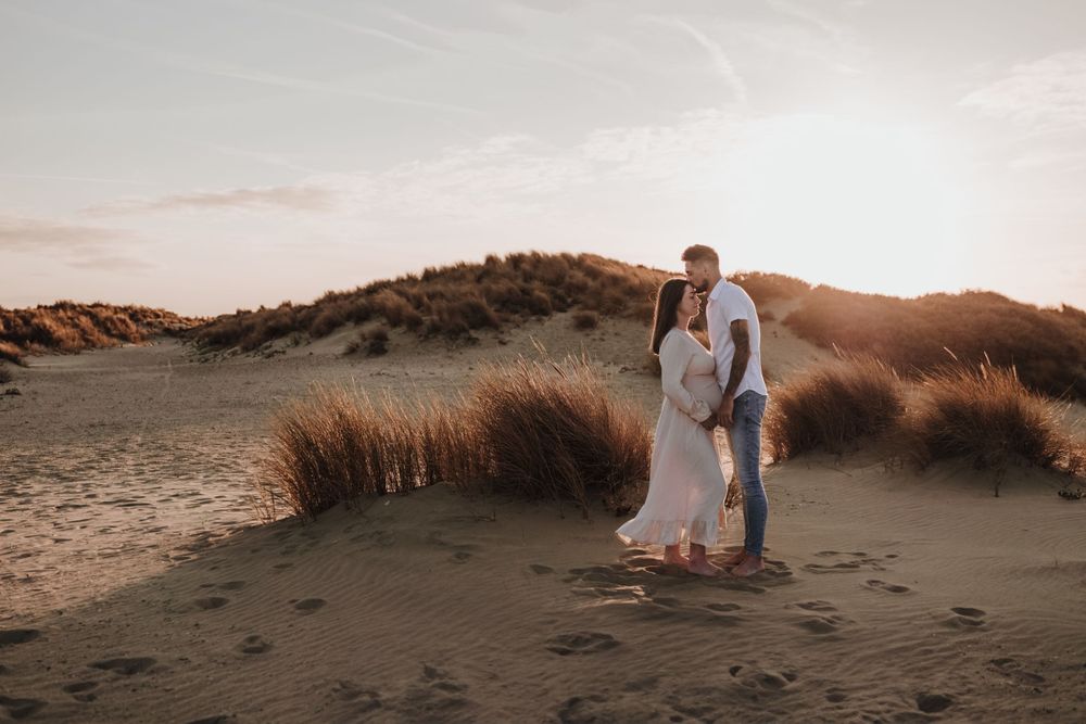 zwangere vrouw met haar vriend/man op het strand van hoek van holland, tijdens zonsondergang