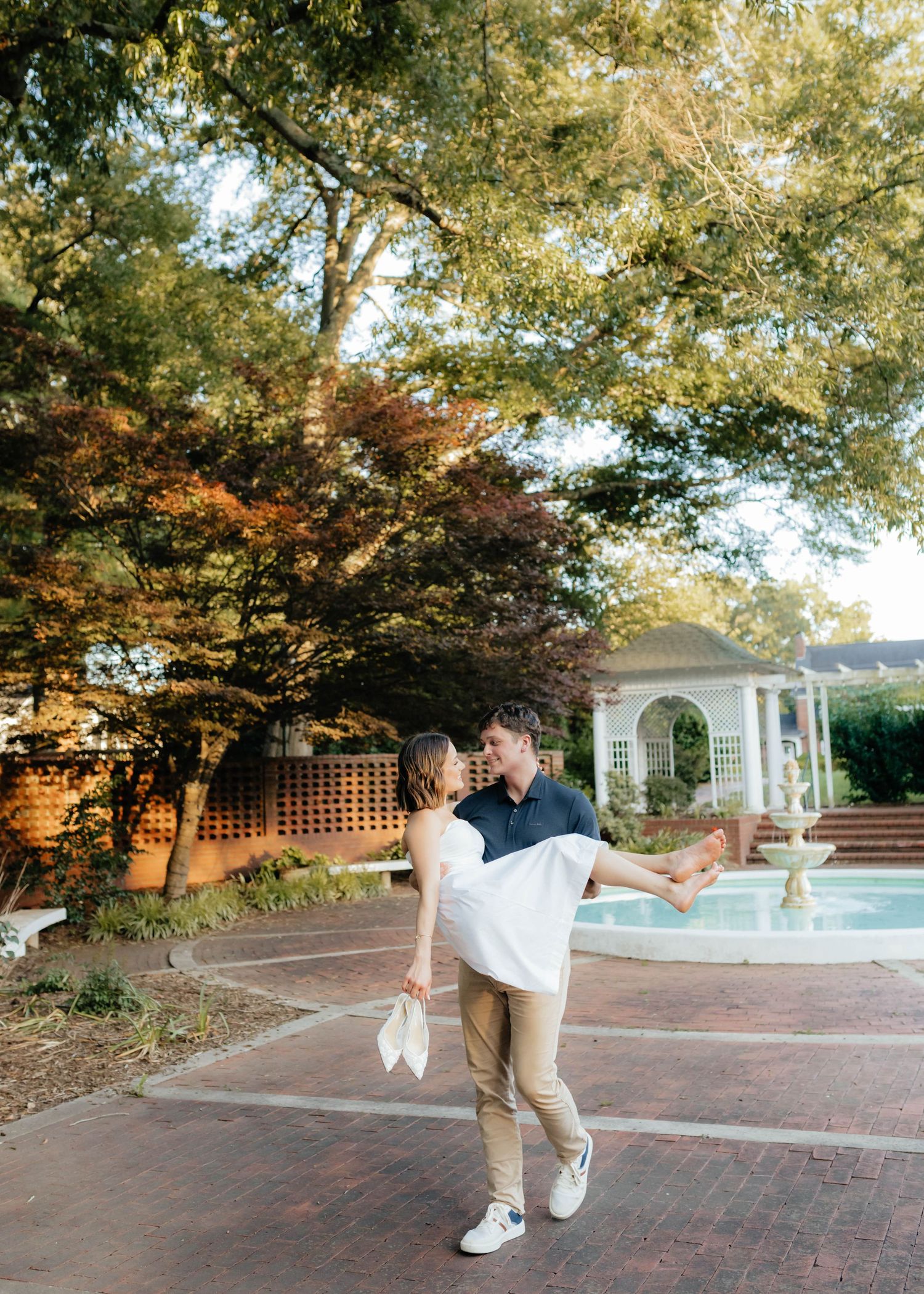 Casual wedding couple dancing and twirling by a garden gazebo and fountain.