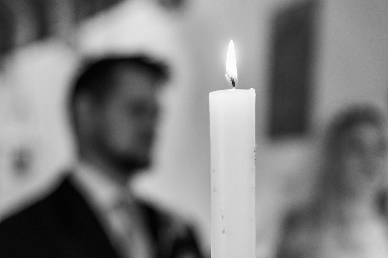 Single white candle burning with soft focus background at wedding ceremony.