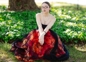 Elegant floral ball gown in red and black photographed in garden setting with spring flowers.