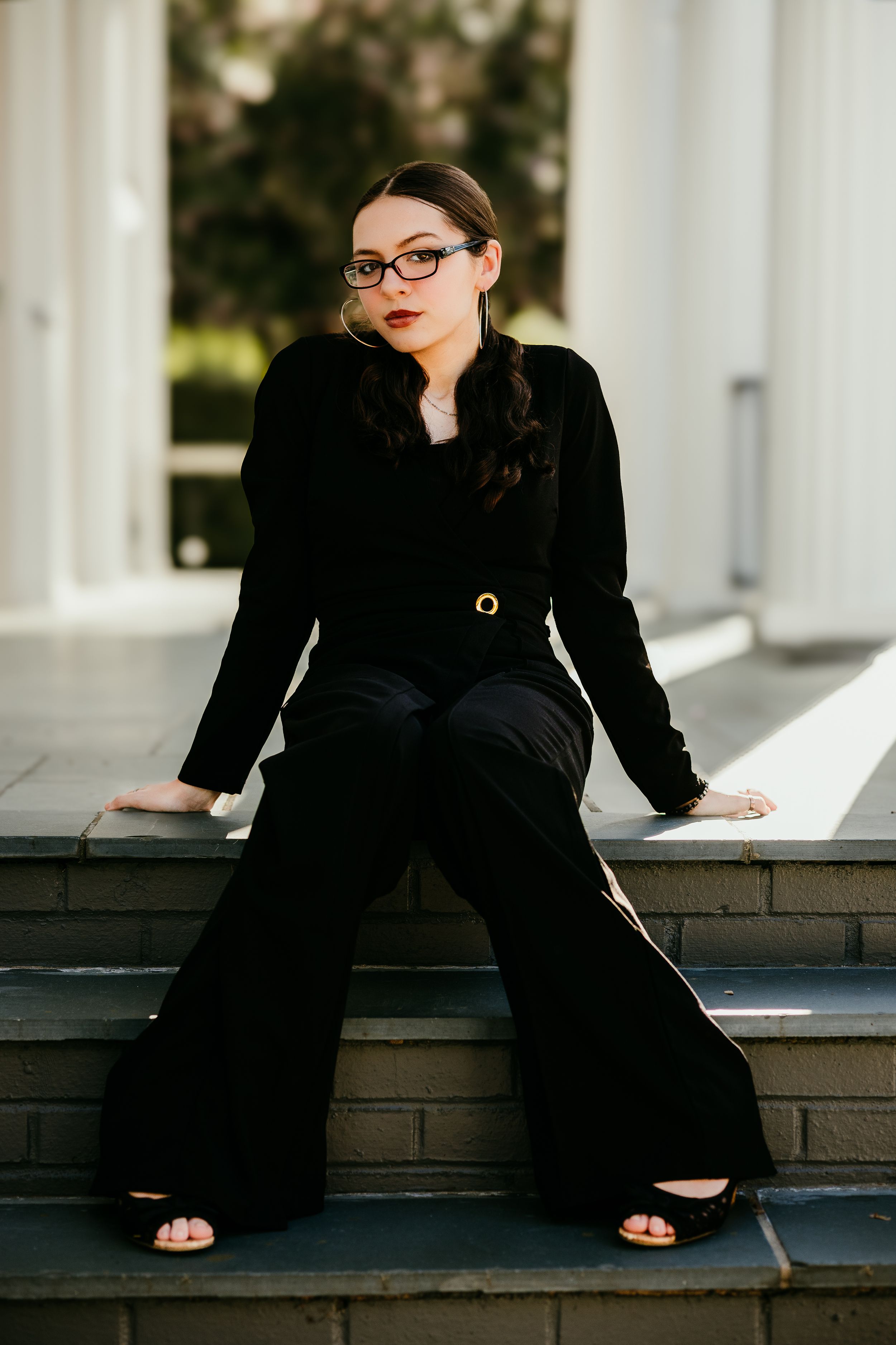 Stylish outfit featuring black sweater and wide-leg pants against architectural backdrop.