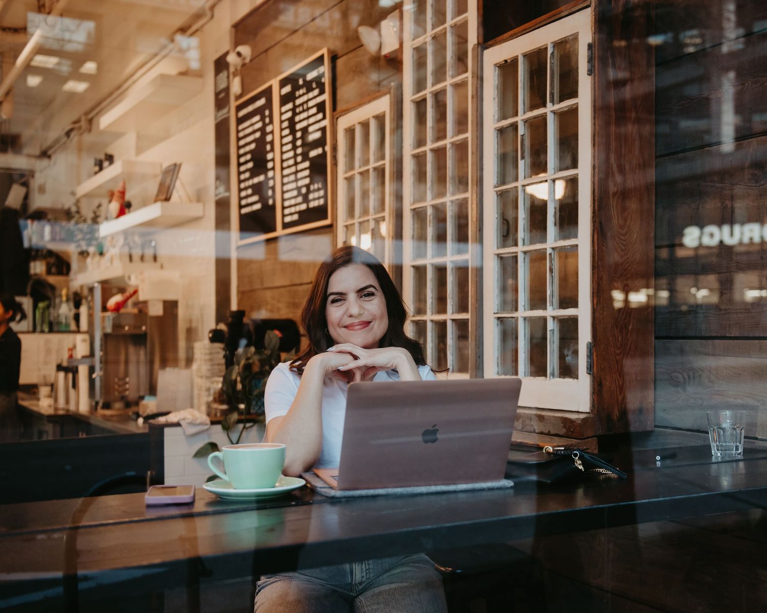 Casual workspace scene at a coffee shop counter with laptop and coffee cup.