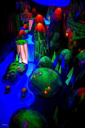 A colorful mushroom fantasy scene glows with neon blue and green lights under blacklight illumination, creating a magical atmosphere.