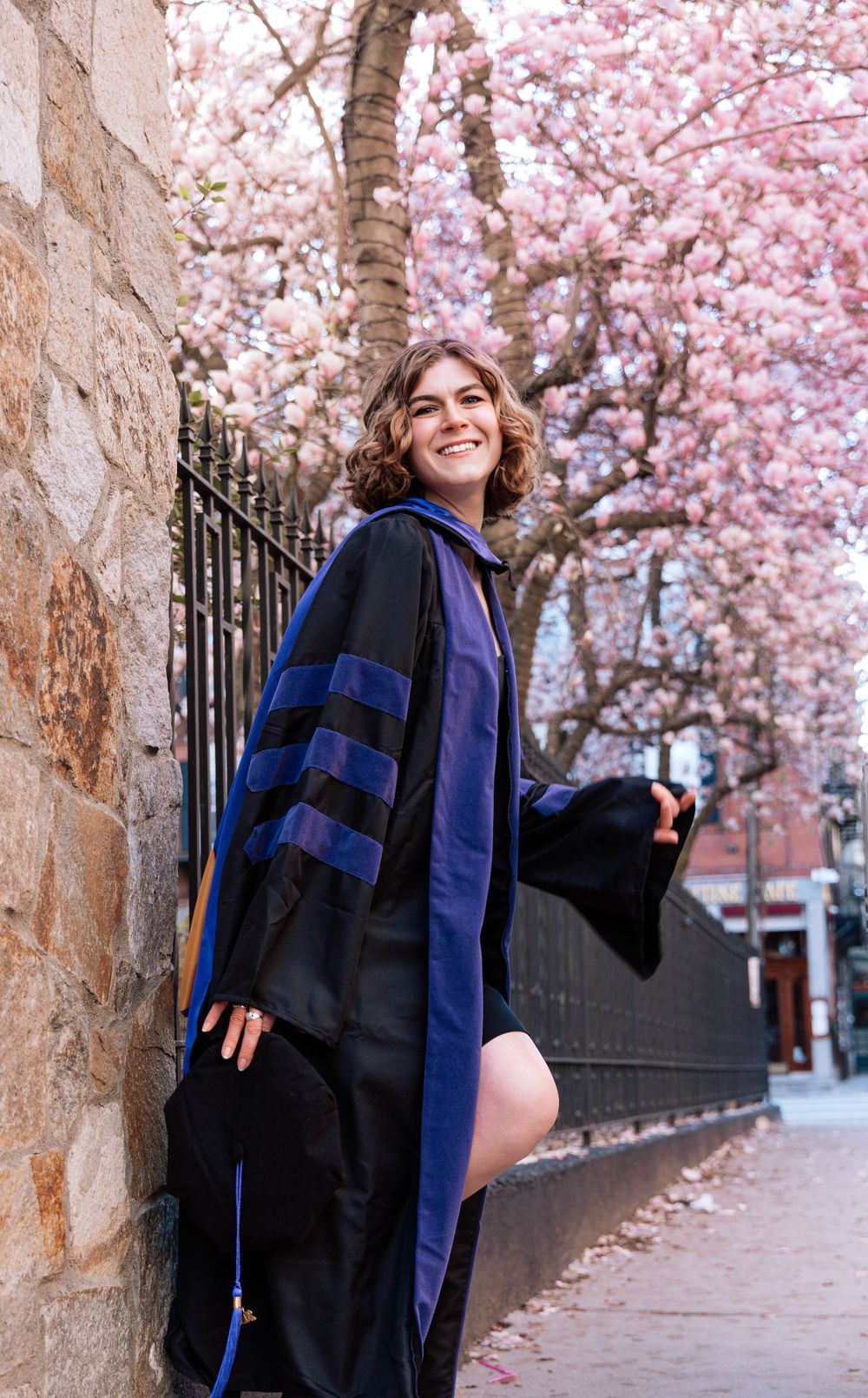 Graduation photos in Boston’s North End with law student in cap and gown, cherry blossoms in full bloom.