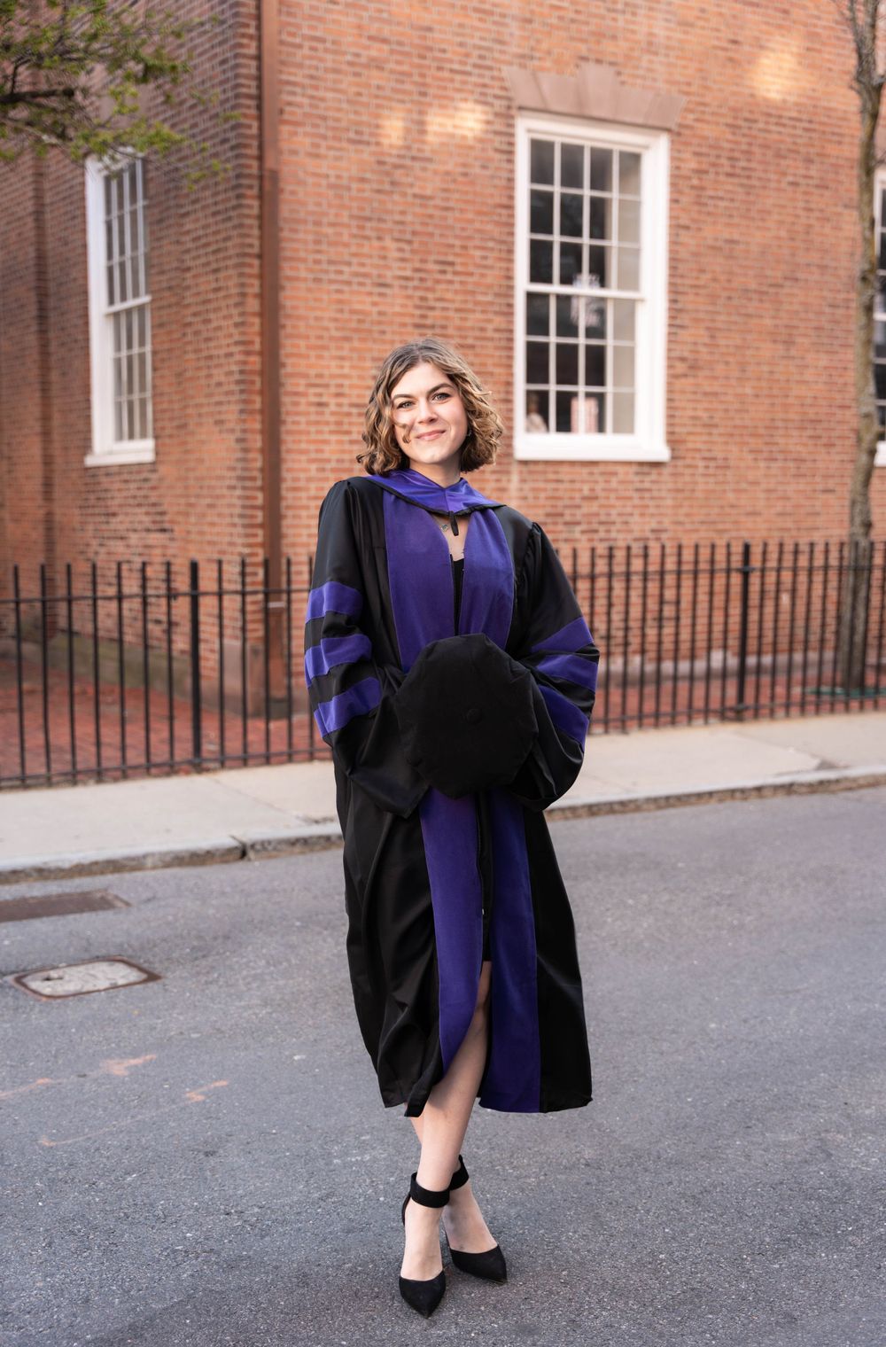 Graduation photos in Boston’s North End with law student in cap and gown, cherry blossoms in full bloom.