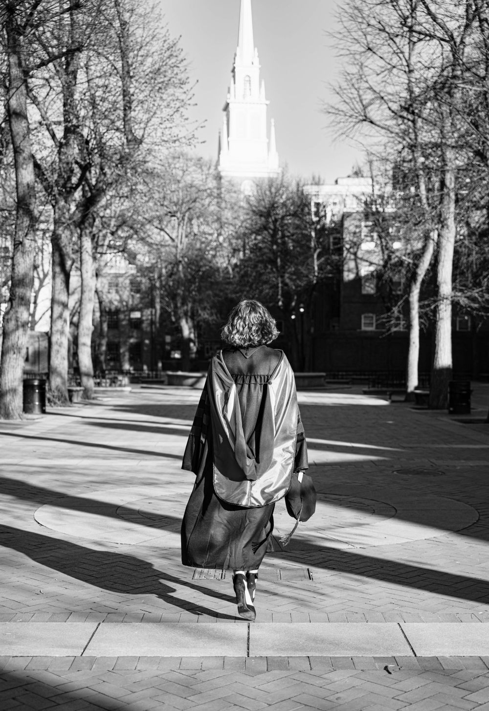 Graduation photos in Boston’s North End with law student in cap and gown, sunrise peeking through.