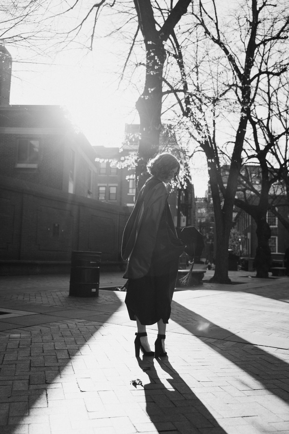 Graduation photos in Boston’s North End with law student in cap and gown, sunrise peeking through.