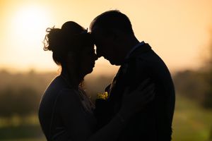 Romantic silhouettes of a couple embracing against a golden sunset backdrop.