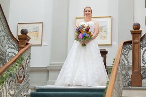 An elegant staircase with ornate railings provides a backdrop for a wedding photo session.