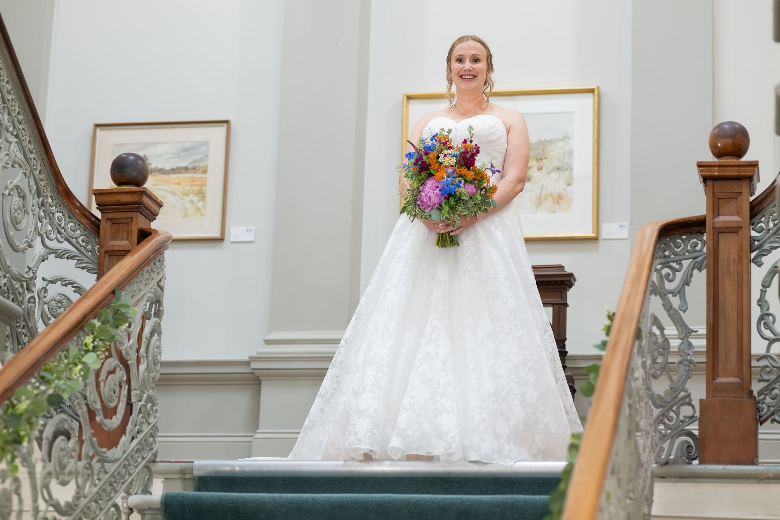 An elegant staircase with ornate railings provides a backdrop for a wedding photo session.
