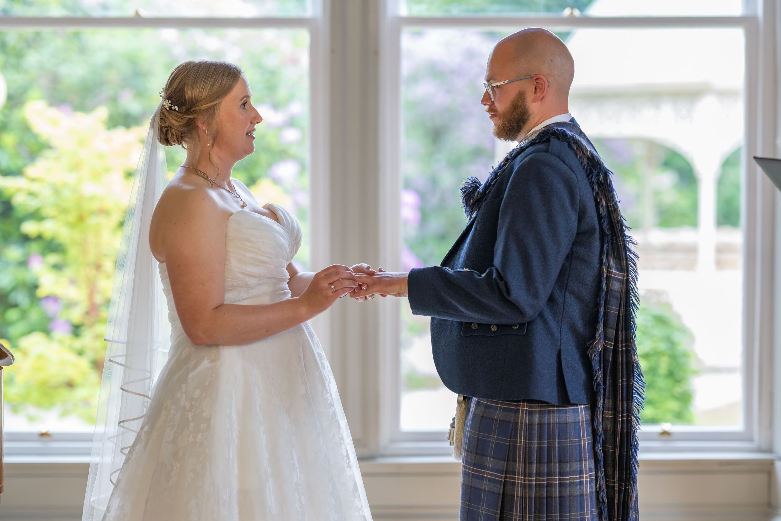 A couple shares a special first look moment in a bright sunlit room with large windows.