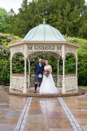 A beautiful white gazebo with intricate lattice work serves as a romantic wedding venue setting.