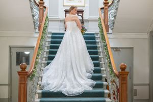 An elegant staircase with decorative railings creates a grand wedding photo setting indoors.