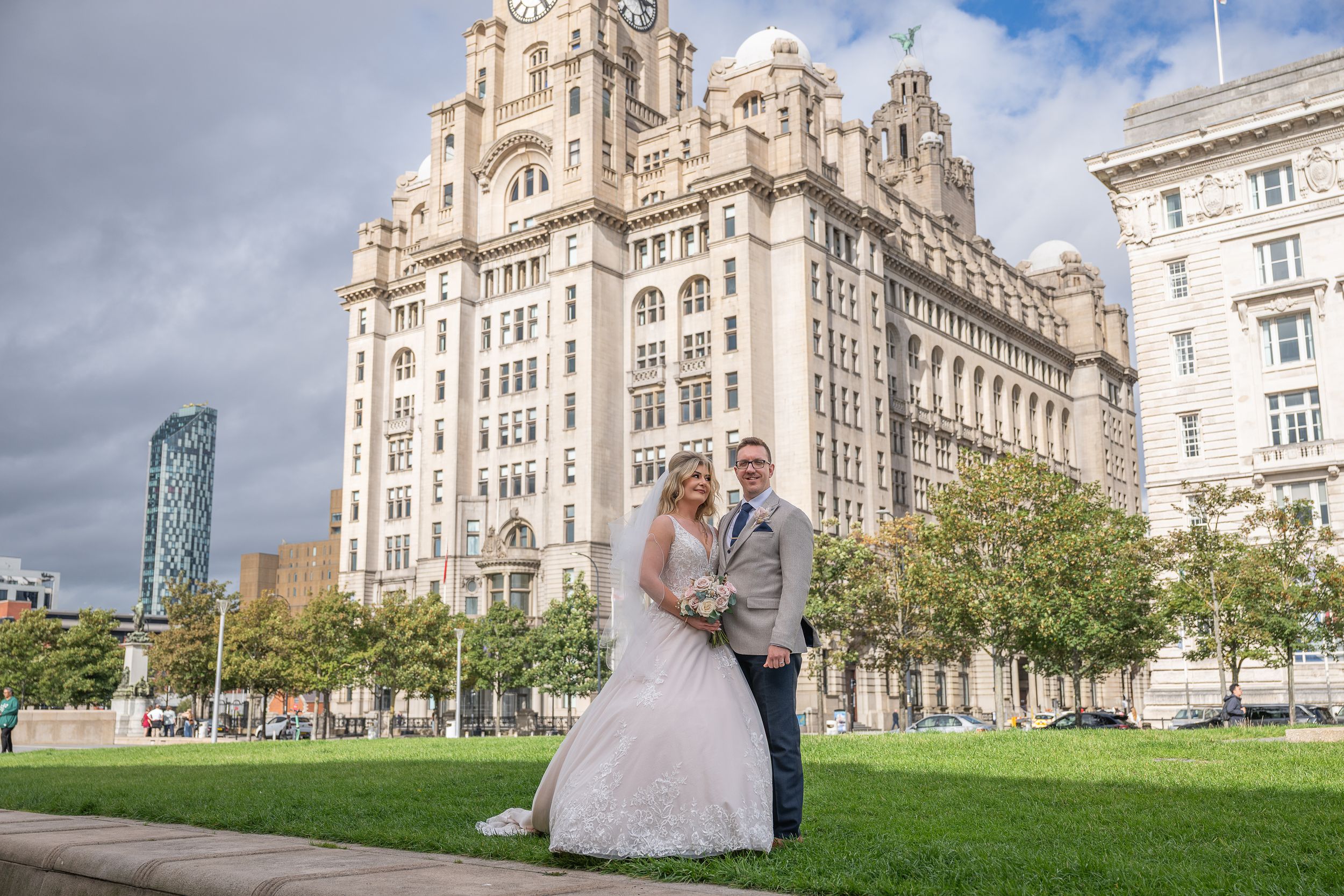 Bride and groom posing in front of the Royal Liver Building in Liverpool on their wedding day.