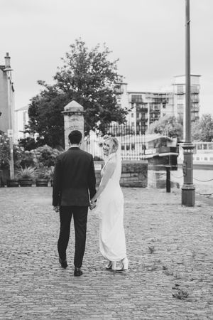 A couple walking together on cobblestone streets in black and white photography.